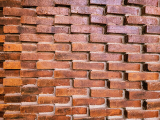 Textured red brick wall with a staggered layout and visible mortar lines, offering a rustic and industrial backdrop ideal for architectural or interior design themes.