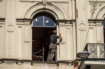 A window fitter in a window opening prepares to install a new window in a building.