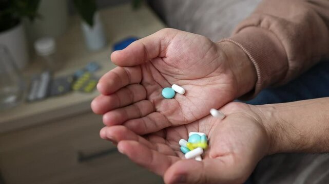 A large handful of pills fall into the hands of a man