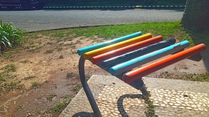 Vibrant park bench with multicolored wooden slats, ideal for outdoor seating and public space illustrations.