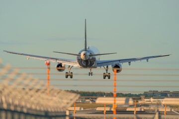 Airplane landing on runway at sunset.