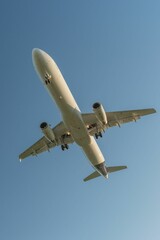 Low angle view of a commercial airplane flying against a clear blue sky.