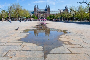 Amsterdam Netherlands - 19 May 2023 - The Rijksmuseum at the Museumplein in Amsterdam in the Netherlands mirrored in a big puddle in an empty pond in front of the museum on a sunny spring day