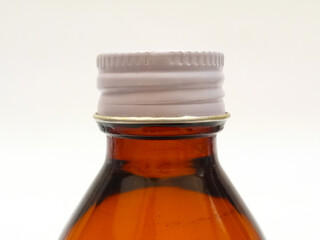 Amber glass bottle with an aluminum cap isolated on a white background, closeup, brown glass bottle for pharmaceuticals, syrups, essential oils, and cosmetics