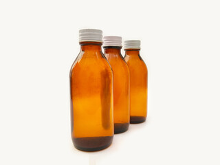 Amber glass bottles with an aluminum cap isolated on a white background, 3 brown glass bottles for pharmaceuticals, syrups, essential oils, and cosmetics