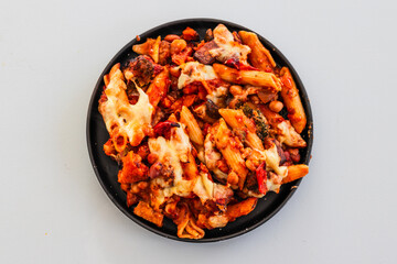 cheesy pasta bake with mediterranean vegetables and beans on black plate