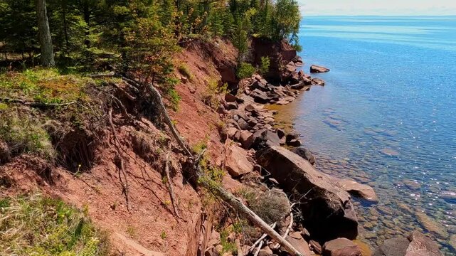 A breathtaking view of Madeline Island Lake Superior shoreline, with crystal-clear turquoise water, rocks, and vibrant spring trees, perfect for a scenic getaway
