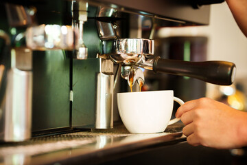 Barista skillfully pouring steamed milk into a cup of espresso, creating latte art in a cozy café during a busy morning.