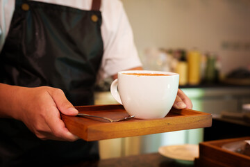 Barista skillfully pouring steamed milk into a cup of espresso, creating latte art in a cozy café...