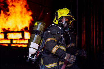 firefighters wearing fire fighter suit for safety and using twirl water extinguisher for fighting the fire flame in emergency situation.. - Safety Firefighter and industrial concept.