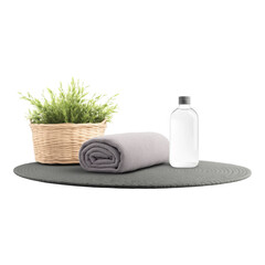 Yoga mat with rolled towel, water bottle, and wicker basket with green plants create serene and calming setup for relaxation or exercise