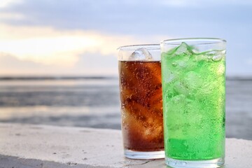 Green and cola soft drink and ice cubes