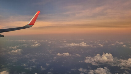 View From Airplane Window of Wing During Sunset. Sky Above Clouds with Vibrant Colors.