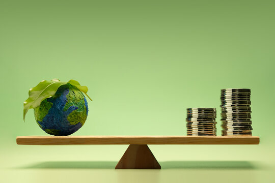Sustainable, Green investment, green finance, and eco-friendly economic growth. Coin money Stack and Green Leaf Globe balanced on a scale