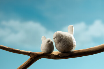 Mother and baby birds perched on branch, symbolizing family love, motherhood, care, and emotional bonding in nature