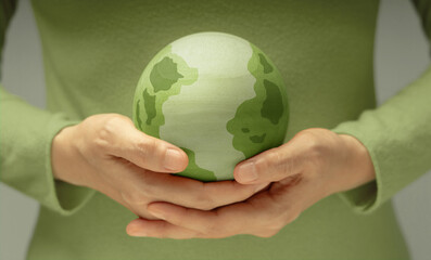 Green earth held gently in hands, symbolizing environmental conservation, care for the planet, and sustainability