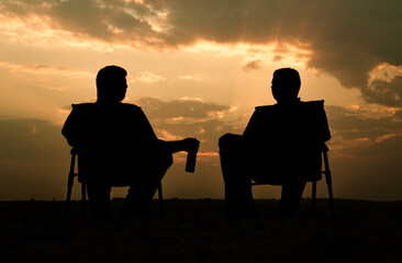 Obraz premium silhouette of a couple sitting on a bench at sunset