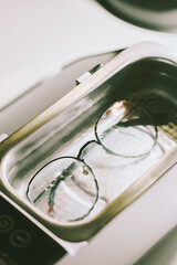 Metal-framed glasses submerged in cleaning solution