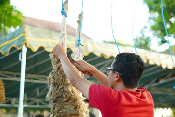 A man skinning a sacrificial goat that was hung on a pole during Eid al-Adha