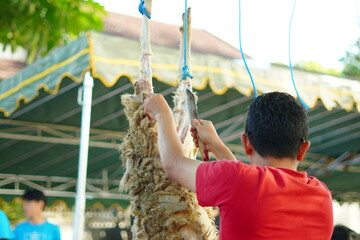 A man skinning a sacrificial goat that was hung on a pole during Eid al-Adha