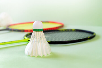 Badminton sport equipments, rackets and shuttlecocks, on badminton floor of indoor court, soft focus.