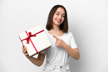 Young Ukrainian woman holding a gift isolated on white background and pointing it