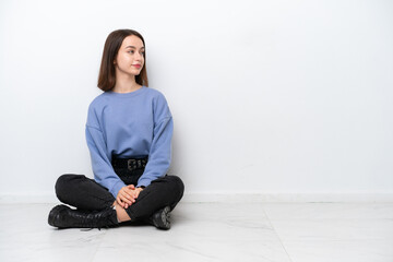 Young Ukrainian woman sitting on the floor isolated on white background in lateral position