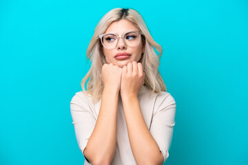 Young Russian woman isolated on blue background With glasses and tired
