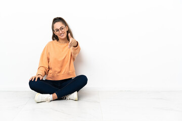 Young woman sitting on the floor shaking hands for closing a good deal