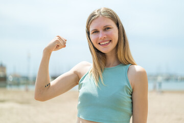 Young blonde woman at outdoors doing strong gesture