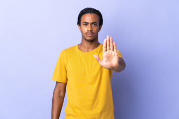 Young African American man with braids man isolated on purple background making stop gesture