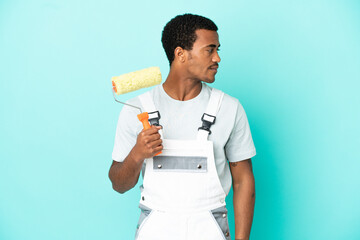 African American painter man over isolated blue background looking to the side