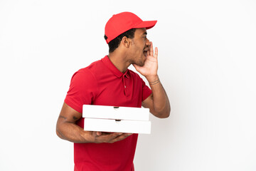 African American pizza delivery man picking up pizza boxes over isolated white wall shouting with...
