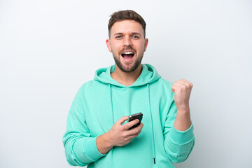 Young caucasian man isolated on white background with phone in victory position