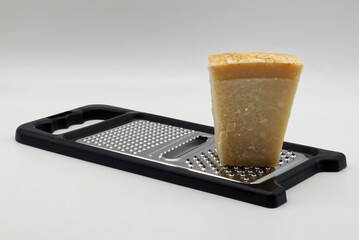Italian Parmigiano Reggiano cheese ready to be grated on a black grater