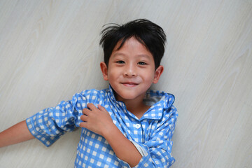 Portrait of happy Asian boy kid lying on floor background with looking at camera. Close-up shot.
