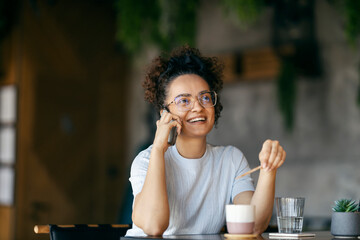 Portrait of interracial young woman sitting in cafe and talking on her phone.