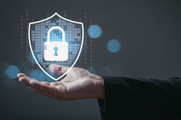 A hand holds a digital shield with a padlock, symbolizing cybersecurity and data protection in a technology-focused environment.
