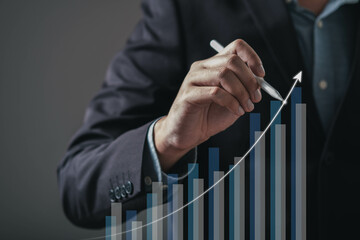 A business professional analyzes a growth chart, indicating upward trends with a pen, symbolizing success and strategic planning.