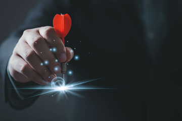 A hand holding a dart aims at a glowing target, symbolizing focus and precision in achieving goals.