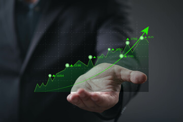 A business professional presents a hand with a rising graph, symbolizing growth and success in financial markets.