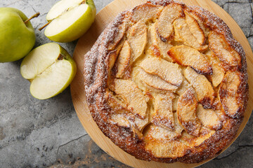 Caramelised apple clafoutis with vanilla and cinnamon close-up on a wooden board on the table. Horizontal top view from above