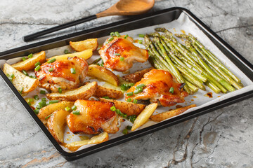roasted chicken with potatoes and green asparagus close-up of a baking sheet on a table. horizontal