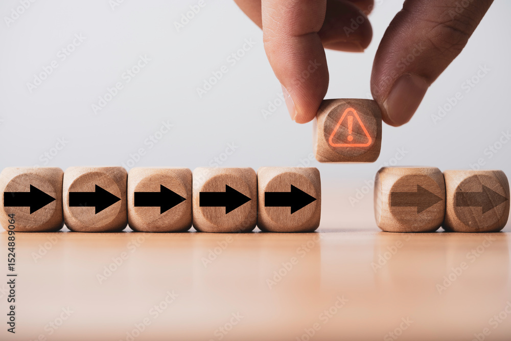 Poster hand holding red glowing exclamation warning sign to stop black arrow moving on delay and disruption