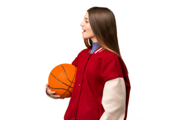 Teenager girl playing basketball over isolated chroma key background laughing in lateral position