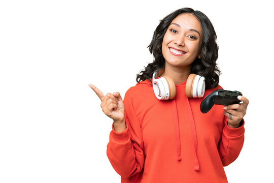 Young Argentinian woman playing with a video game controller over isolated background pointing finger to the side