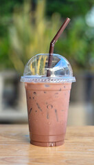 Iced Chocolate, Cocoa in clear plastic cup on wooden table in the garden.