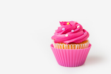 Brightly pink decorated cupcake with icing swirls and colorful sprinkles