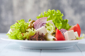Simple salad with tomatoes, feta cheese , red pepper and fresh herbs. Bright wooden background. Close up.	