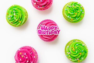 Top view of cupcakes with birthday topper on white background